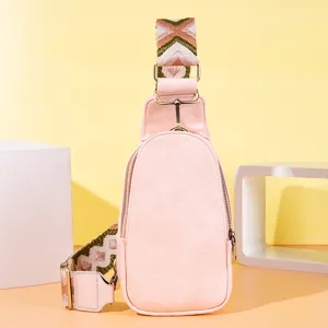 Primer plano de un bolso de pecho retro rosa con una correa ancha de patrones coloridos