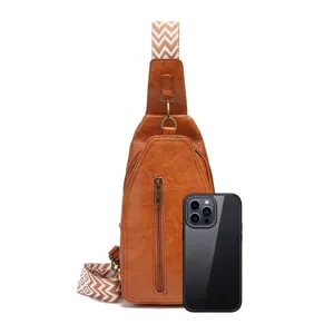 Riñonera retro marrón con correa bohemia junto a un smartphone para comparar tamaño.
