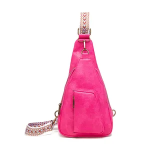 Bolso bandolera fucsia vibrante con correa ancha con motivo bohemio y cremalleras metálicas.