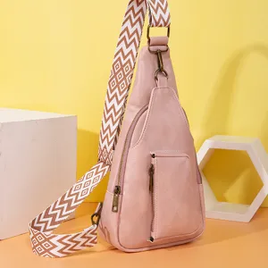 Detalle de bolso bandolera de piel sintética rosa con correa ancha con motivo bohemio