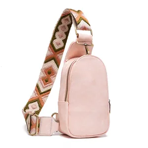 Detalle de bolso de pecho rosa con correa ancha con estampado étnico retro.