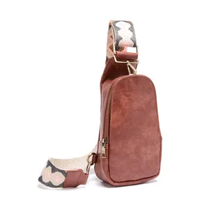 Detalle profesional de un bolso bandolera vintage de cuero marrón con correa ancha estampada