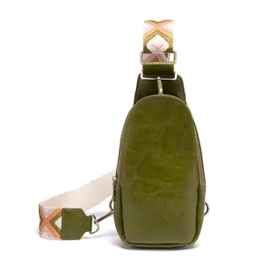 Detalle de bolso de pecho verde vintage con correa ancha tejida con patrones