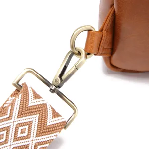 Detalle de correa tejida boho y gancho de oro antiguo en bolso bandolera marrón.