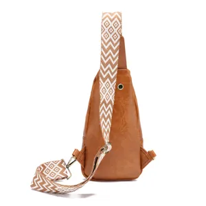 Detalle de bolso bandolera de cuero PU marrón con correa de patrón bohemio en blanco.