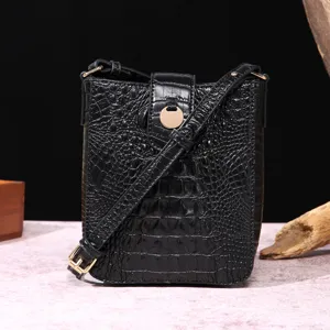 Detalle de bolso para móvil negro con relieve de cocodrilo y broche dorado