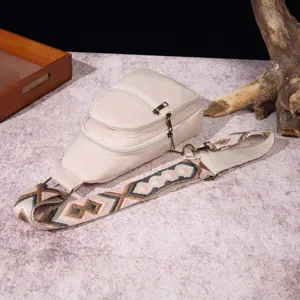 Detalle de bolso bandolera beige con correa bordada bohemia