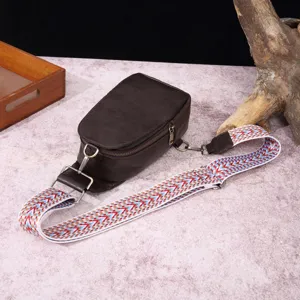 Detalle de bolso de pecho marrón vintage de cuero sintético con correa ancha estampada