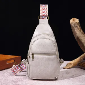 Primer plano de un bolso bandolera de cuero PU gris claro con correa tejida bohemia.
