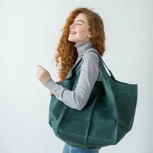 Bolso tote grande de cuero encerado verde oscuro llevado por una modelo sobre fondo blanco