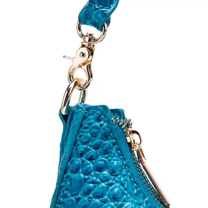 Dettaglio ravvicinato di borsa blu con trama coccodrillo e hardware in metallo dorato