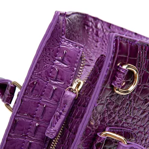 Primer plano de un bolso morado con relieve de cocodrilo y cremallera dorada