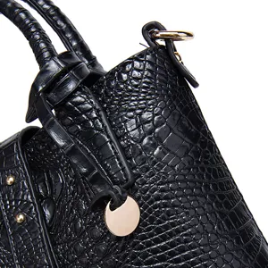 Detalle de primer plano de bolso de cuero grabado de cocodrilo negro con herrajes dorados