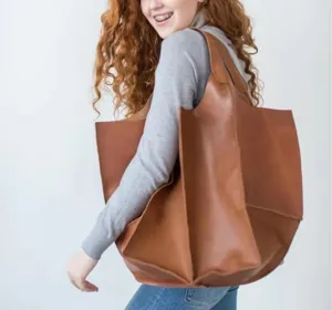 Vista detallada de un bolso tote grande de cuero marrón en el hombro de una modelo