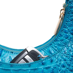 Dettaglio borsa blu motivo coccodrillo con zip dorata e chiave dell'auto all'interno.