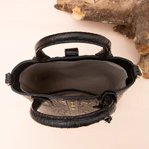 Detalle superior del bolso negro con relieve de cocodrilo y forro interior gris