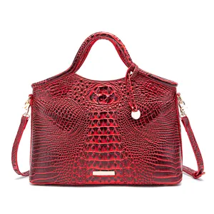 Vista detallada de un bolso rojo con grabado de cocodrilo y elegantes herrajes dorados