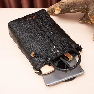 Detalle de bolso negro con relieve de cocodrilo mostrando espacio para una tablet