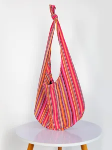 Detalle de un vibrante bolso hobo de jacquard con rayas aztecas sobre una mesa blanca.