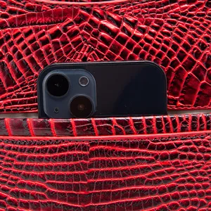 Primer plano de bolso rojo con relieve de cocodrilo y un útil bolsillo trasero