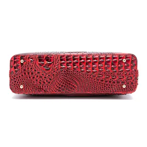 Detalle inferior de bolso rojo con grabado de cocodrilo y cuatro pies de metal dorados