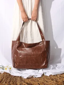 Detalle de un bolso tote grande vintage de cuero encerado con bolsillo frontal