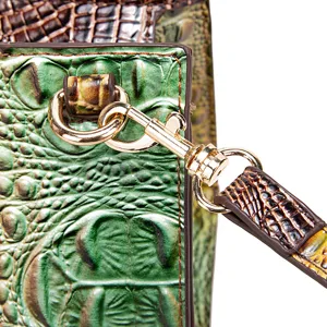 Detalle del cierre de metal dorado en un bolso de mano con relieve de cocodrilo verde