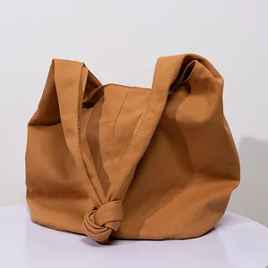 Bolso tote grande de lona color ocre con diseño holgado y detalle de nudo frontal