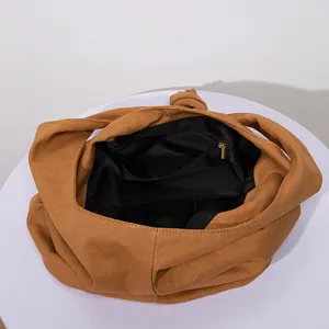 Vista detallada del forro interior negro y el bolsillo con cremallera del bolso de lona marrón