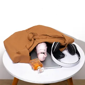 Primer plano de bolso hobo de lona marrón con artículos diarios que muestran gran capacidad