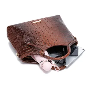 Detalle de bolso marrón con grabado de cocodrilo mostrando la capacidad interior con objetos.