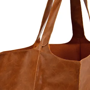 Primer plano de la textura y costuras de un bolso tote marrón de cuero suave con cera vintage