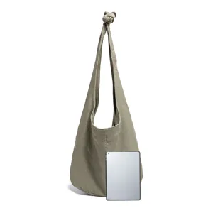 Bolso hobo grande de lona verde oliva junto a una tableta para comparar el tamaño.
