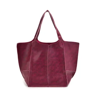 Vista detallada de un bolso tote vintage de cuero aceitado rojo vino suave