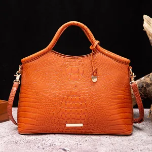 Vista detallada del bolso de mano naranja con estampado de cocodrilo y herrajes oro