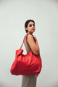 Vista detallada de un gran bolso tote vintage de cuero rojo encerado llevado por modelo
