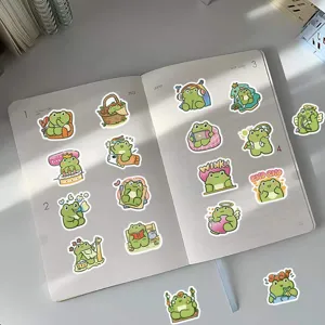 A collection of cute cartoon frog stickers decorating an open white diary on a desk