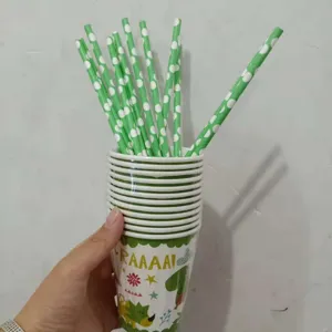 Gros plan de gobelets en papier jetables dinosaure et de pailles vertes à pois festifs