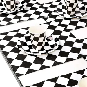 Détail de gobelets et assiettes de fête à damier noir et blanc sur le thème de course.