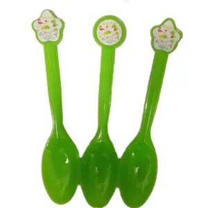Détail de cuillères en plastique vert pour enfants avec motifs de dinosaures sur le manche.