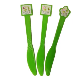 Détail de couteaux en plastique vert avec motif de dinosaure pour fête d'enfants.