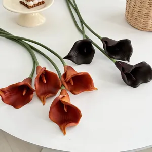 Gros plan de fleurs de lys calla artificielles en PU orange et violettes pour la décoration