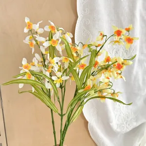 Close-up of delicate white and yellow artificial orchid flowers with green variegated leaves