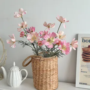 Close-up of pink artificial cosmos flowers in a straw basket for home decor