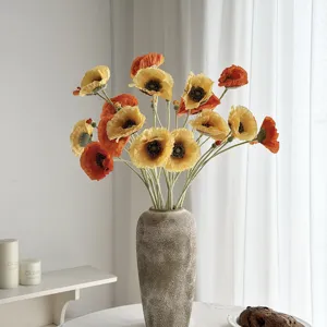 Vista detallada de flores de amapola artificiales con pétalos naranjas y amarillos