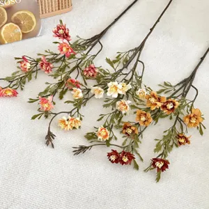 Detailed view of artificial autumn-colored wild chrysanthemums on textured fabric