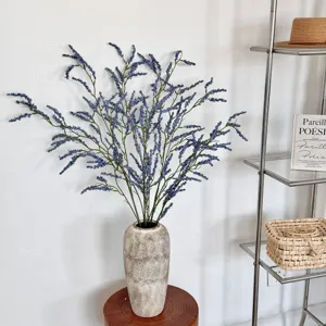 Detailweergave van kunstmatige blauwe lamsoorbloemen in een rustieke keramieken vaas
