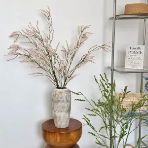Gedetailleerd overzicht van elegante kunstmatige roze rijstgrasbloemen in een keramische vaas