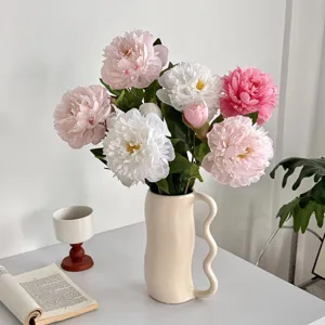 Elegant artificial peony bouquet in minimalist cream ceramic vase for home decor