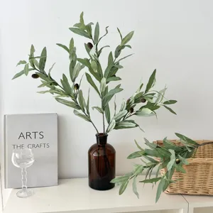Artificial olive branch with green leaves and fruits in a brown glass vase setting.